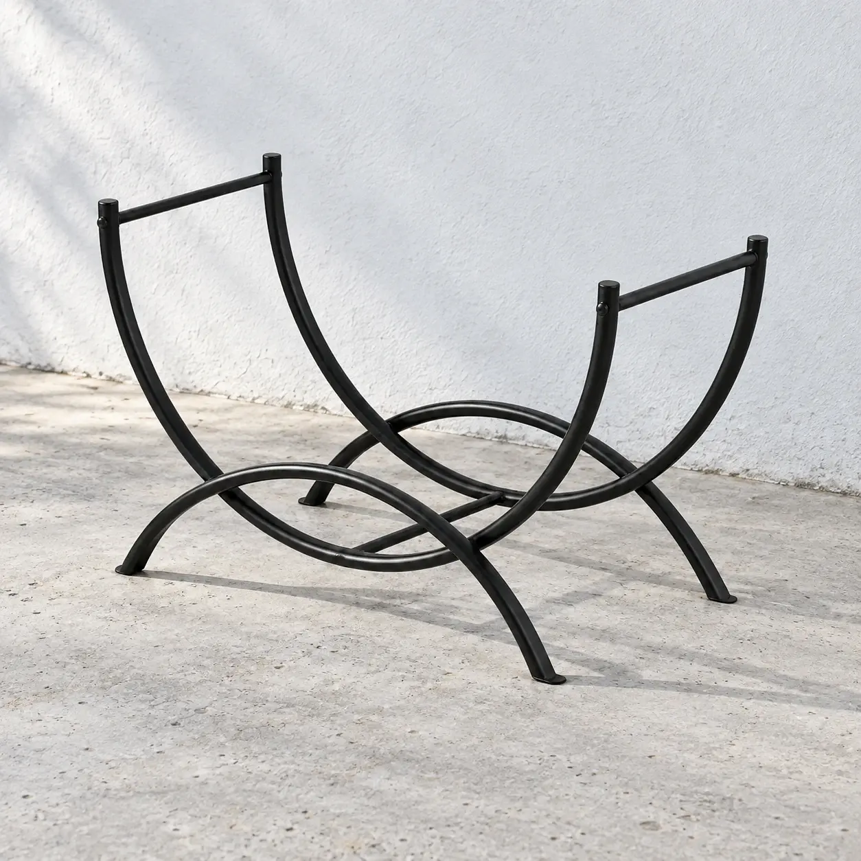 Empty black curved log rack on a pale gray floor