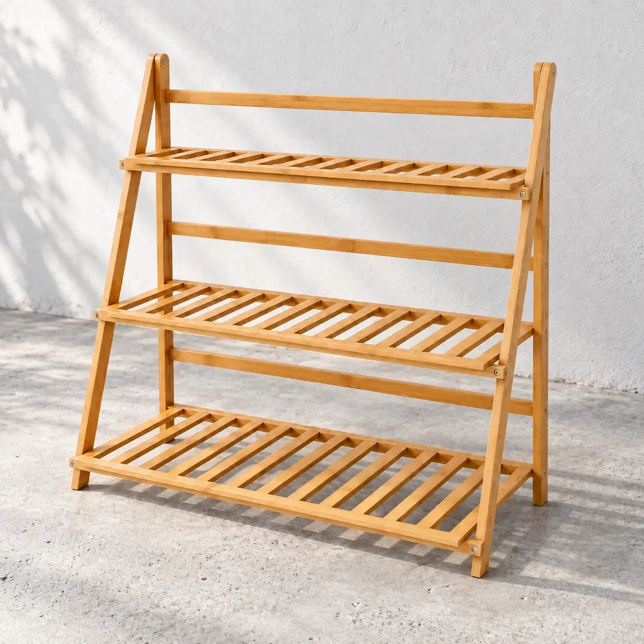 Empty three-tier bamboo plant stand on a pale gray terrace